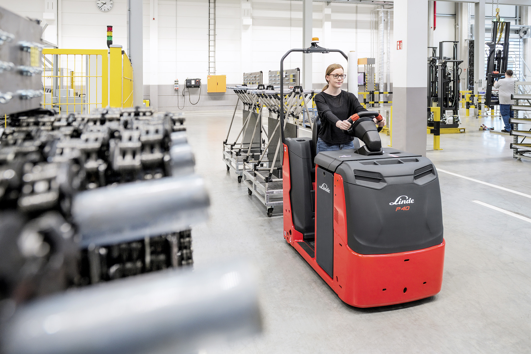 Medewerker Linde in nieuwe elektrische Linde trekker aan het werk in magazijn - Efficiënt intern transport