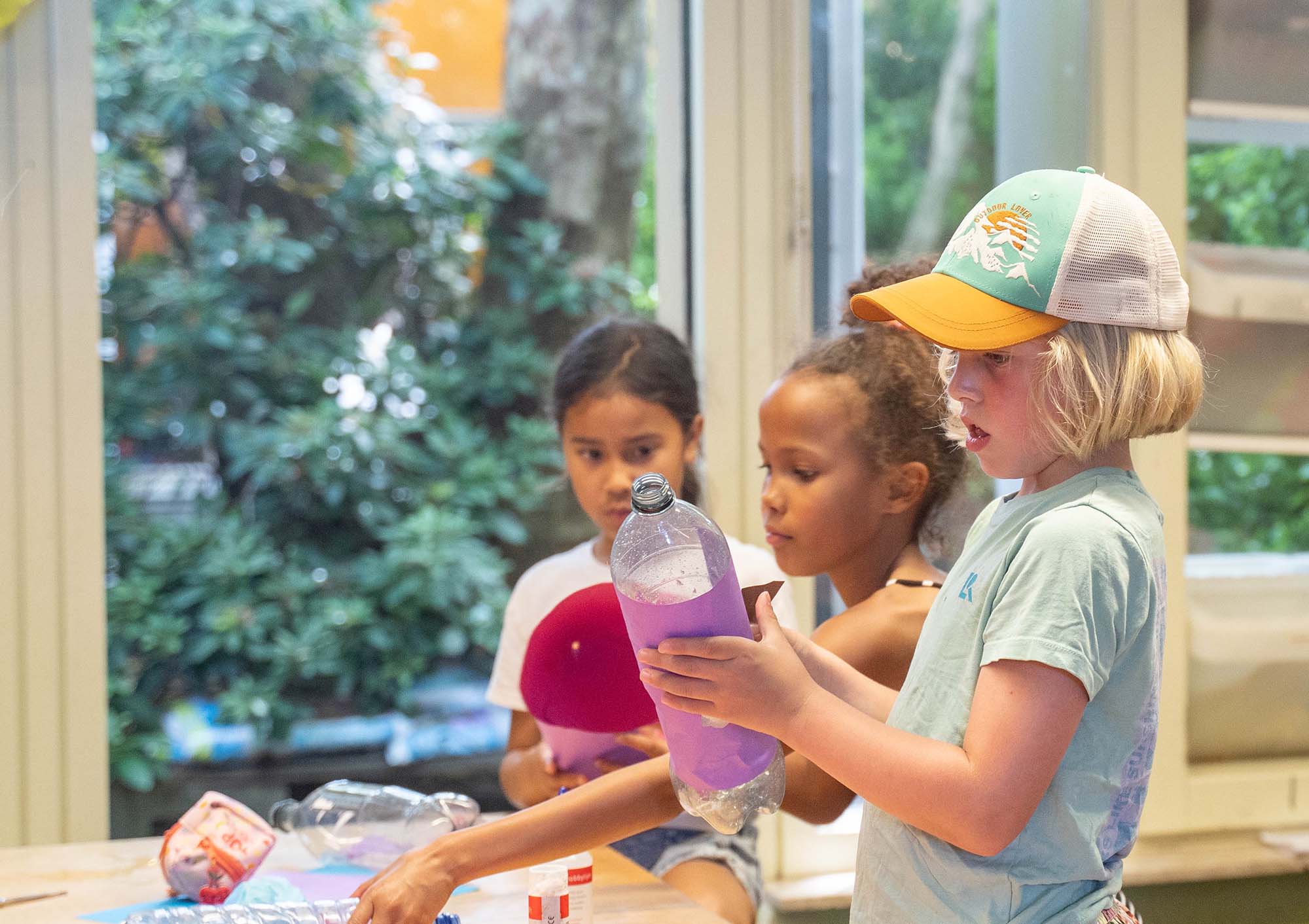 Kinderen knutselen met lege flessen op de BSO.