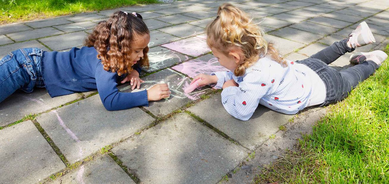 Peuters stoepkrijten bij de peuteropvang.