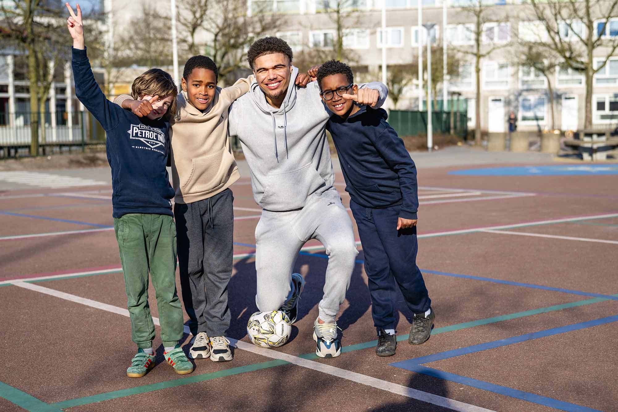 Jongens voetballen met een pedagogisch professional. 