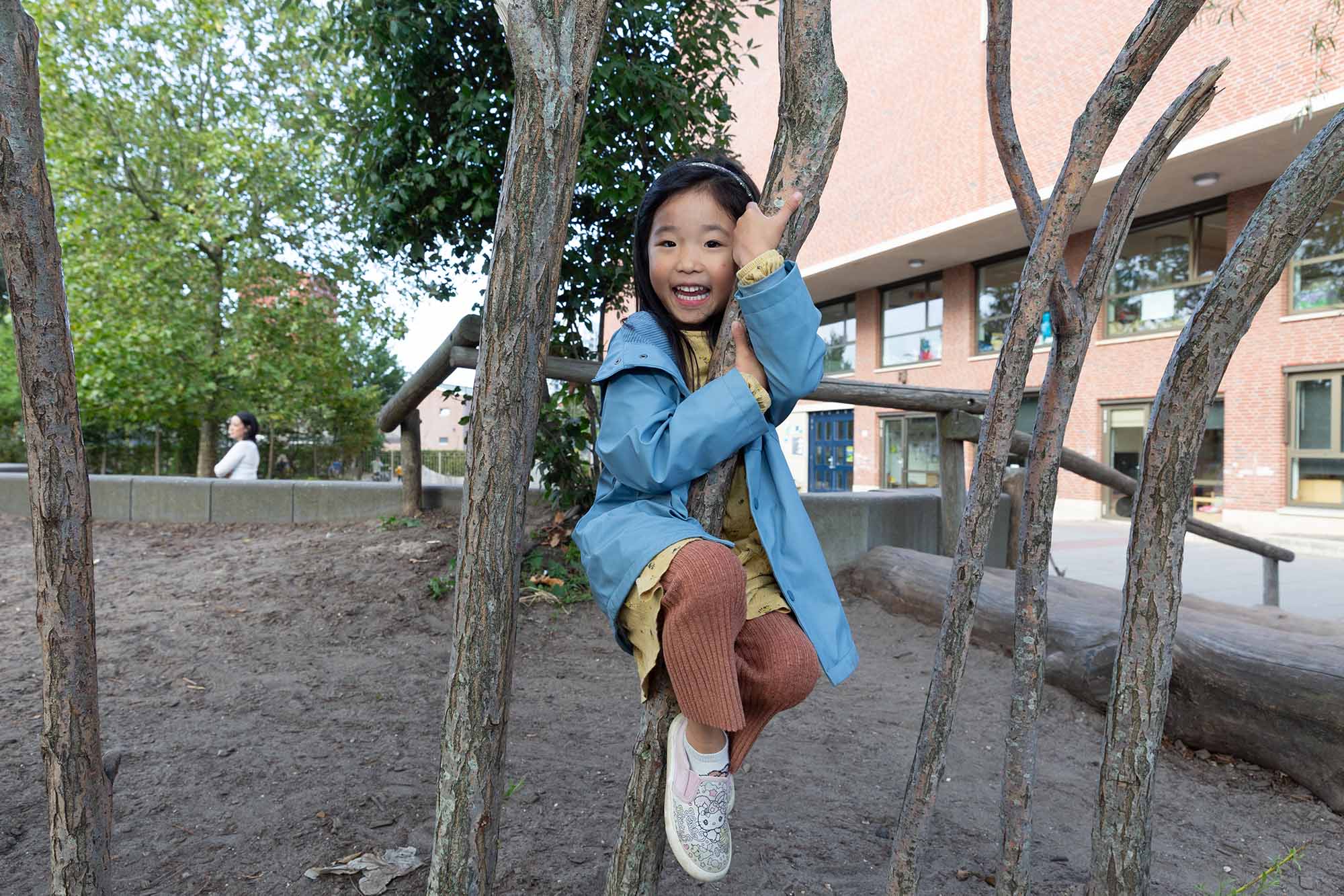 Meisje klimt in een boom van tuin bij kinderopvang locatie.