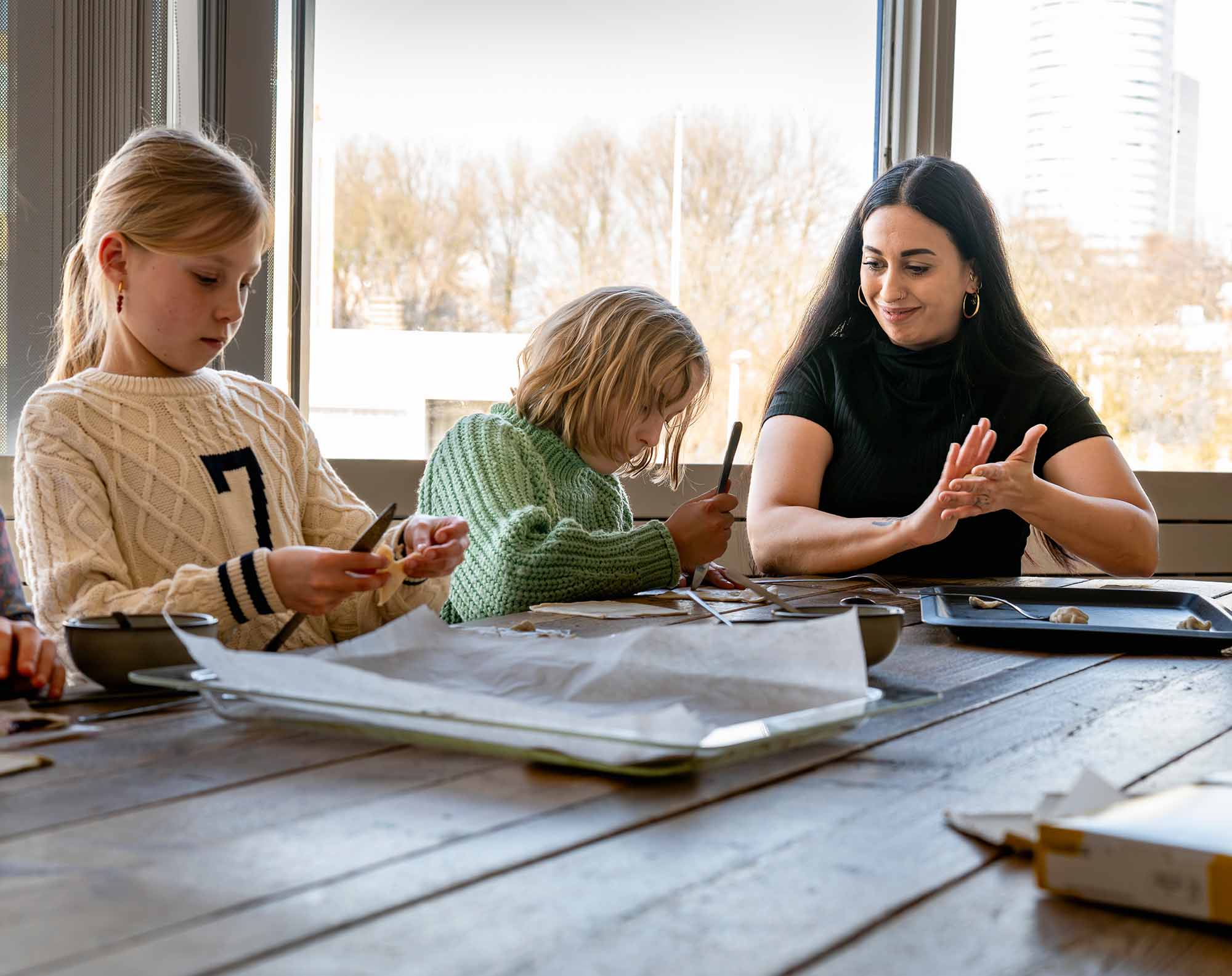 BSO kinderen zitten met een pedagogisch professional aan tafel. 