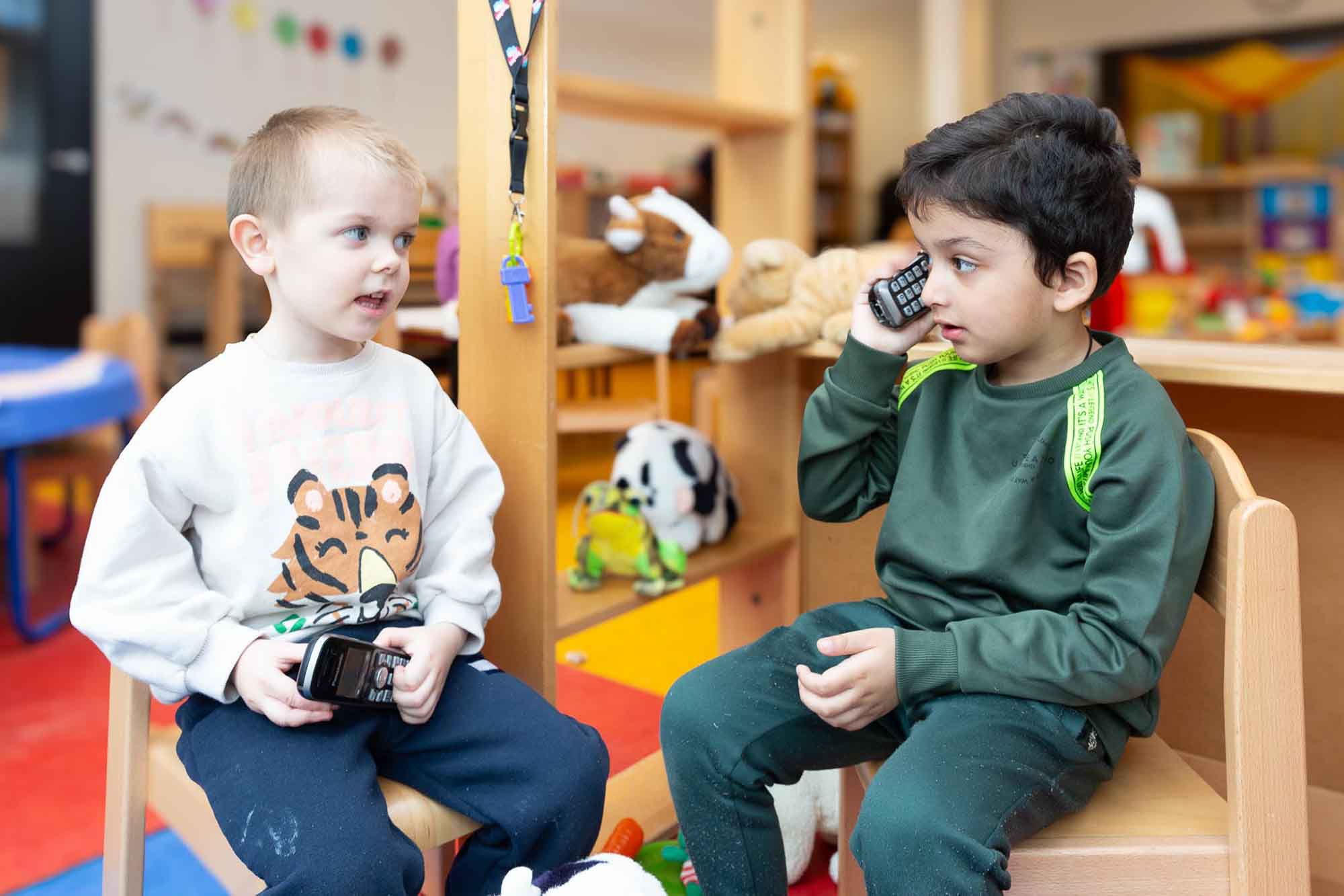 Jongens zitten op een stoel en spelen met een telefoon bij de kinderopvang.