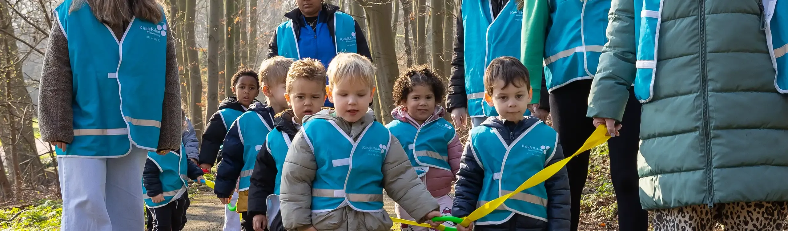 Peuters lopen in een groep buiten met pedagogisch professionals